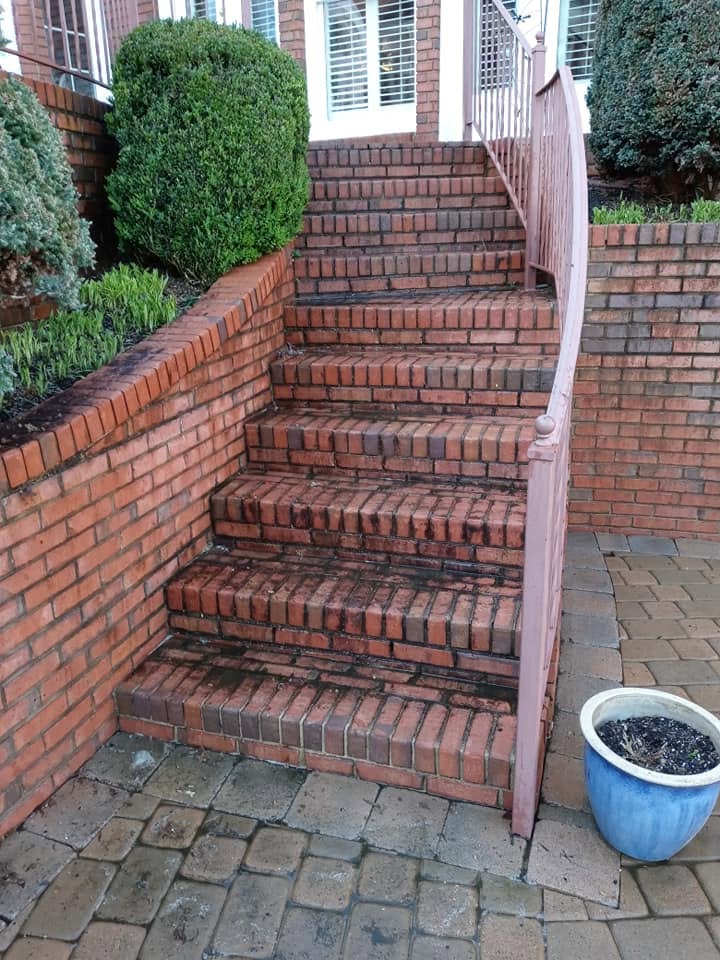 Curved red brick staircase with moss and discoloration before cleaning